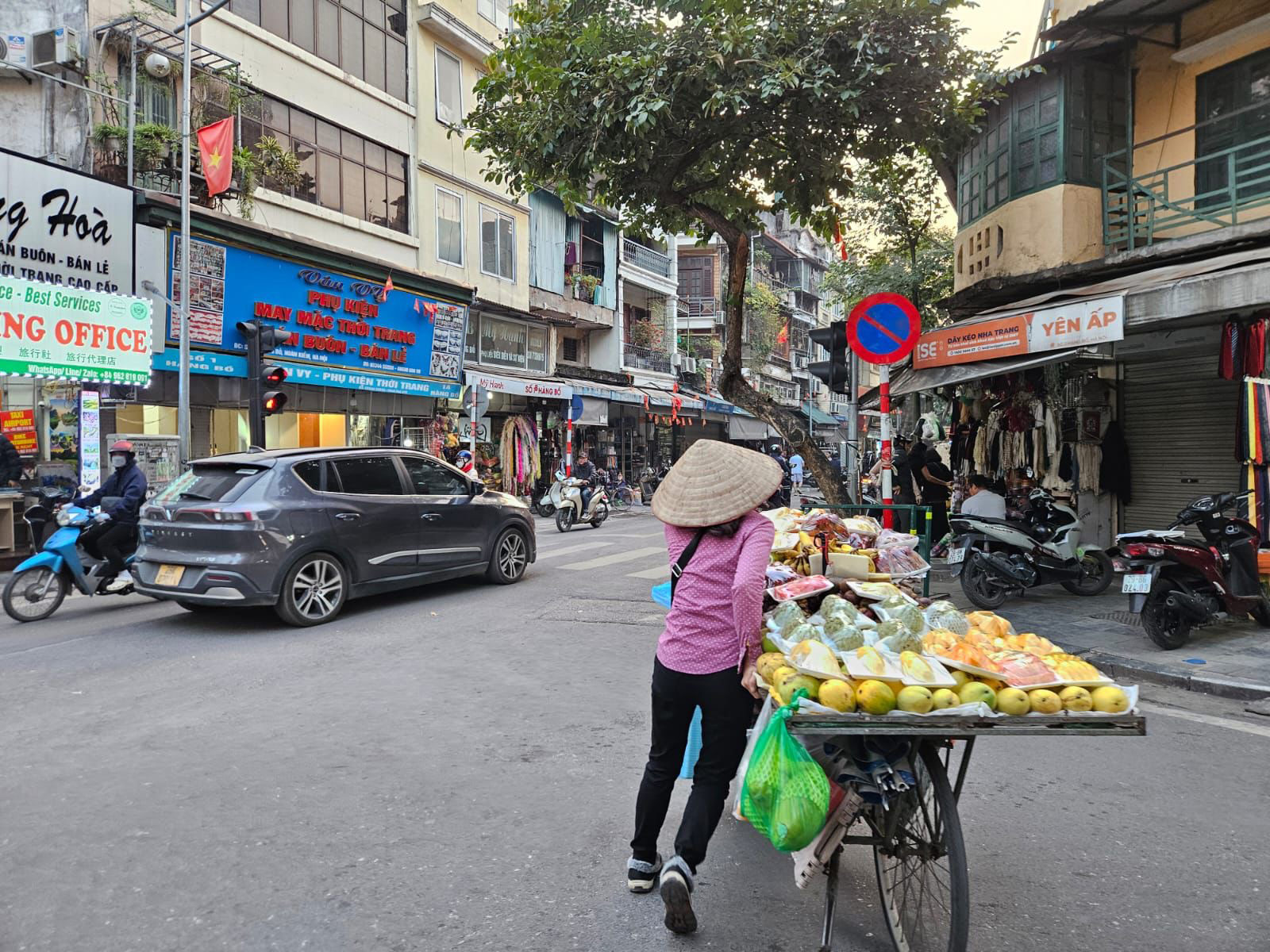 Local street scene in Vietnam with a vendor pushing a fruit cart through a lively neighborhood market