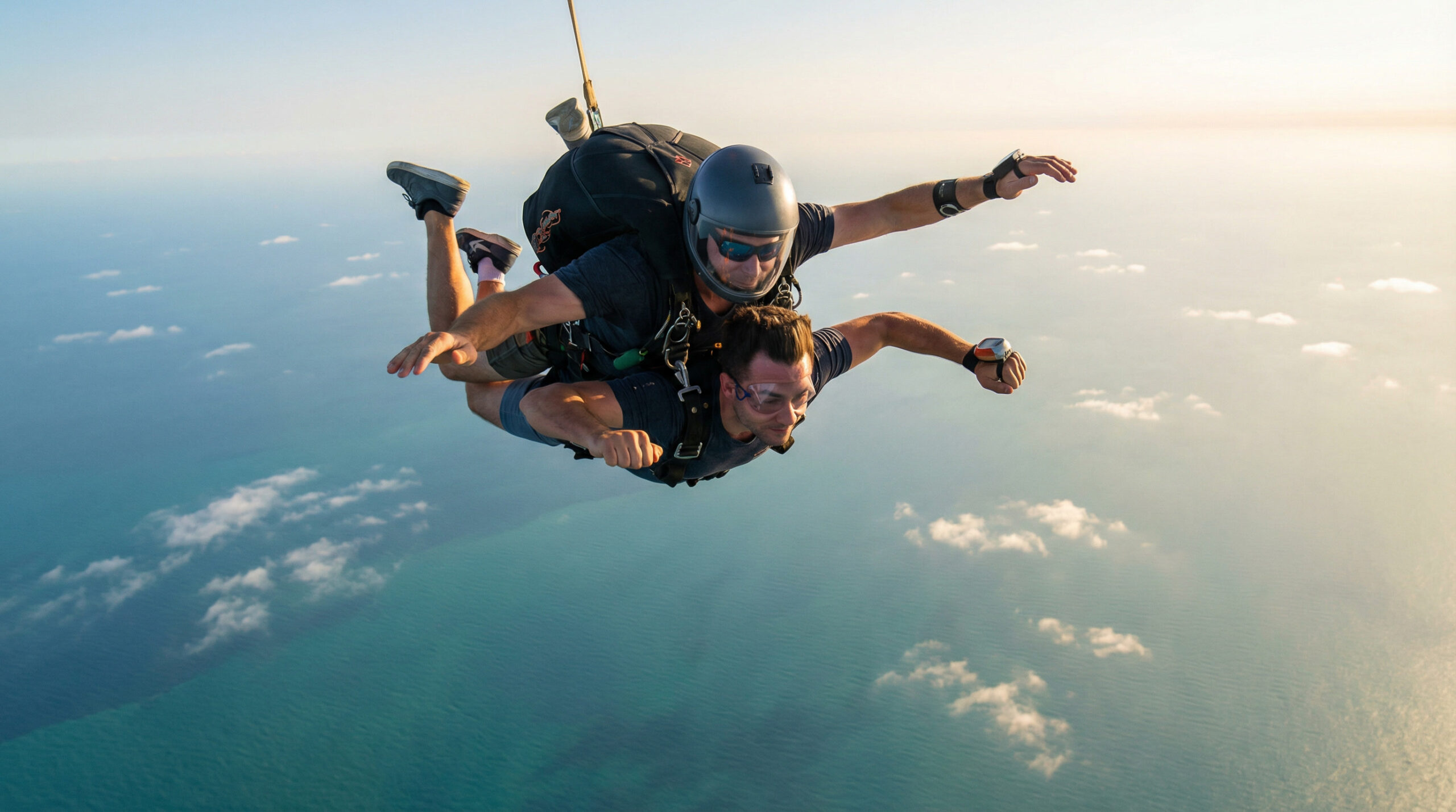 Tandem skydiving experience with professional instructor during freefall over turquoise ocean under warm summer light